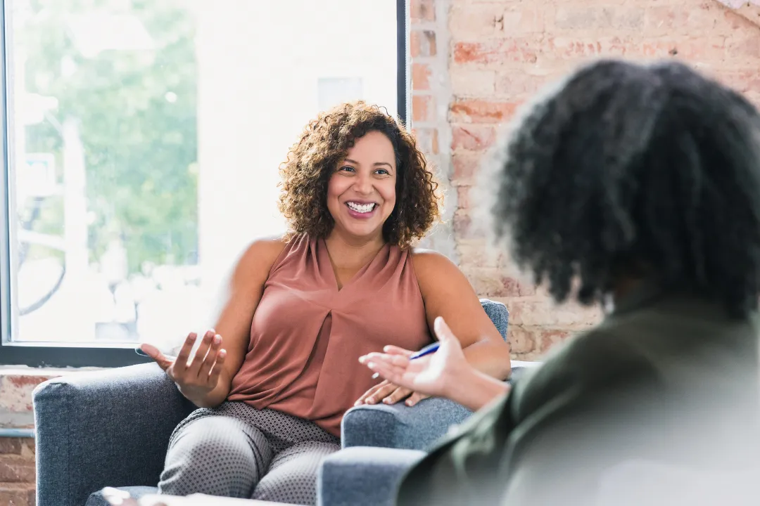 Smiling woman engaged in a one-on-one therapy session during an Intensive Outpatient Program (IOP), seated in a bright, welcoming space in New Hampshire.